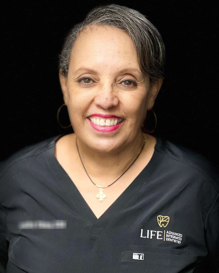 Smiling woman in dental clinic uniform.